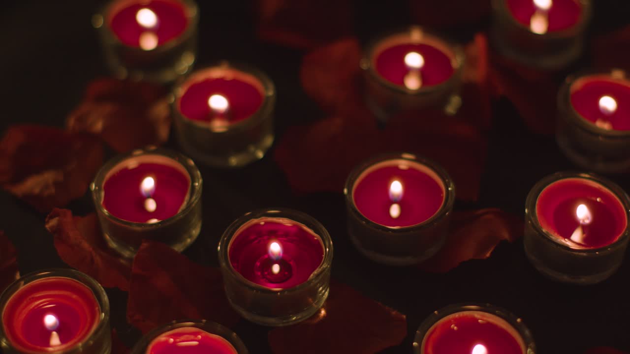 Free stock video - Romantic lit red candles on background covered in